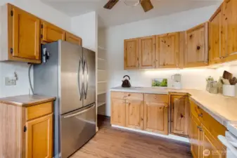 Kitchen offers stainless fridge, generous cabinetry, and NEW LVP flooring. (Virtually staged)