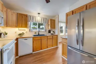 Kitchen view highlights excellent storage, updated appliances, and warm wood cabinetry. (Virtually staged)