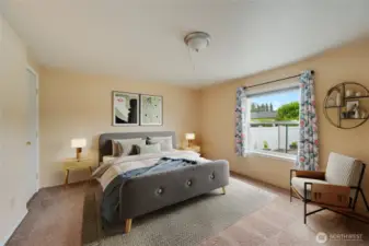 Comfortable primary bedroom with large window and warm natural light. (Virtually staged)