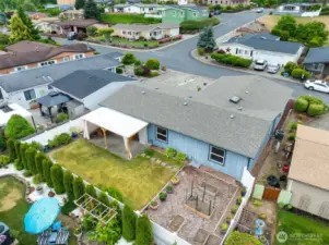 Overhead look at the home, covered patio, raised garden beds, and peaceful setting.