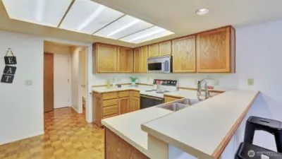 This kitchen showcases beautiful oakwood cabinets that add warmth and character, paired with expansive countertop space perfect for meal preparation, serving, and gathering