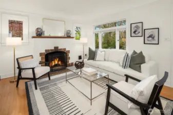 Sun-filled living room with hardwood floors, wood-burning fireplace and leaded glass windows.