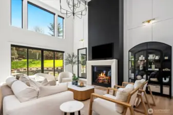 Fireplace in large greatroom, accentlighting; black windows thruought home pronounce the outdoors, views.