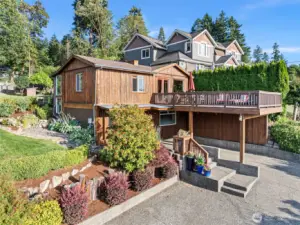 Side view of this charmer and view deck over the carport and paved parking area. A side walkway takes you up to the back entrance and upper level when separate entry is desired.