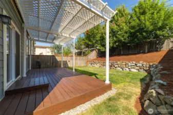 Fully fenced and beautifully manicured backyard with a deck—perfect for relaxing and hosting friends or family gatherings