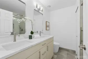 Renovated in 2025, this primary bath features dual vanities, beautiful light fixtures, & custom shower!
