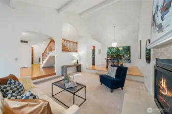 From the very first step, new carpet underfoot sets the tone as vaulted ceilings and large windows enhance this grand living room—complete with a gas fireplace and views into the elevated dining area—perfect for both quiet evenings and lively gatherings.