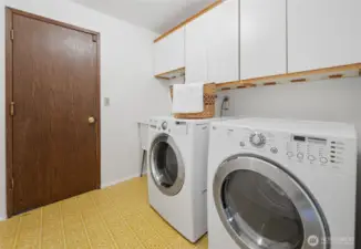 The spacious laundry room is located right off the entry and offers upper cabinet storage, a utility sink, and direct access to the attached two-car garage—making household tasks and unloading a breeze.