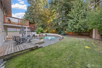 Unwind or entertain on the spacious multi-level deck overlooks the serene pool, surrounded by lush landscaping and tall evergreens!