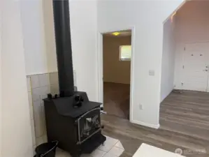 Wood stove and looking into the primary suite with carpeting.
