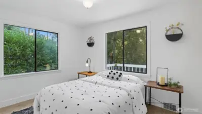 Bright primary retreat with dual windows framing private green views.
