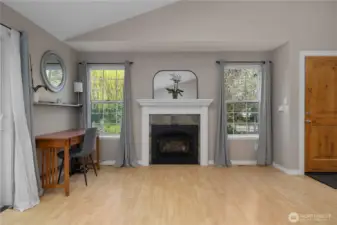 Fireplace and large windows add charm and comfort to this welcoming living space.