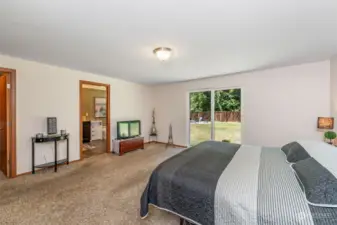 The spacious primary bedroom has a large walk-in closet and en-suite bathroom. In this one-story home, you can walk right out from the primary bedroom into the large fenced yard.