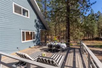 Large wood deck on south side of this home overlooks Pine tree landscape.