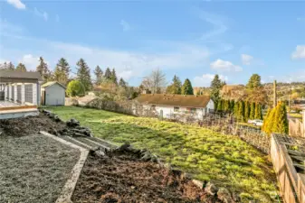 Here is the view of the backyard from the firepit area. There are boxed-in garden planters to the right for those who like growing their own veggies or plants. You'll also notice a large storage shed in the far left corner too!