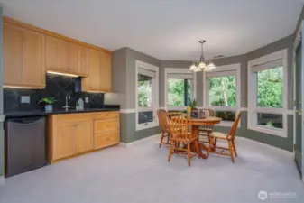 A slab granite beverage center with sink and refrigerator, temperature controlled 700 bottle wine room and door leading to the patio and backyard.