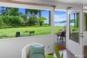 Living room door opens to the patio and lush green grass common area