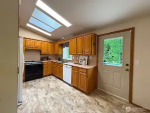 Functional kitchen just off the dining room, with oak cabinetry and garden window framing backyard views.