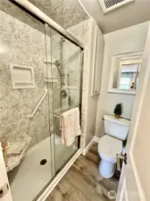 Primary shower/toilet area is updated.  Shower offers large seat and grab-bar.