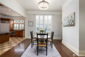 Light-filled dining room with crystal chandelier open to the kitchen.