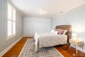Bright bedroom with original wood floors and built in closets.