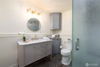 Stylish bath with marble vanity and gold fixtures.