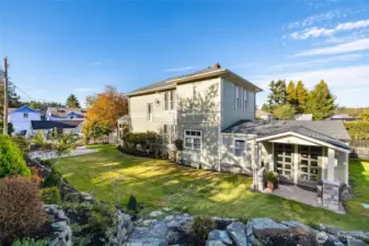 Sunny side yard with stone wall and patio chair.