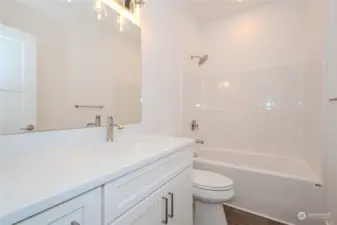 The Full Bathroom in the upstairs hallway boasts excellent storage space, quartz counters, a full bath/shower combo and luxury vinyl plank (LVP) flooring, blending modern style, durability and function.