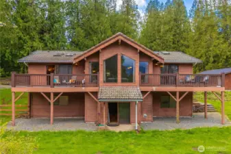Rear view of house shows daylight basement exit and two private upper decks that overlook the forest and mountain views.