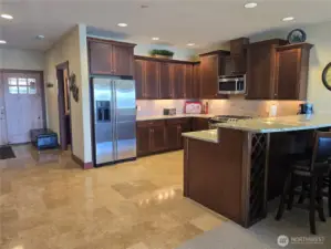 Large kitchen has granite slab counters, undercounter lighting