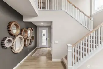 Vaulted entryway with 8-foot glass panel door wows with open railing along the stairs. Photo is representational. Actual home is under construction and finishes will vary. See site agent for details.