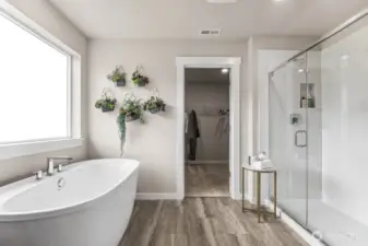 5-piece primary bathroom with double vanity, freestanding bathtub, waterproof flooring, and step-in designer shower. Photo is representational. Actual home is under construction and finishes will vary. See site agent for details.