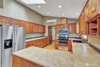 Light and bright kitchen with vaulted ceilings, custom cabinetry, hardwood floors, and stainless steel appliances.