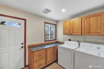 Oversized laundry room with extra storage and door to backyard.