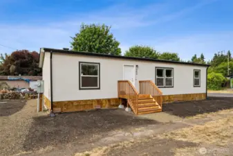 Brand new 2025 home on a corner lot. There is a front yard, then parking to the left and a large side yard behind that.  The parking sots are to the left of the front door.