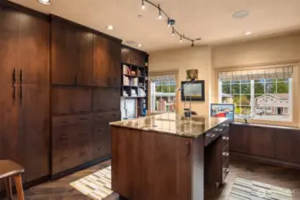 The home office is impeccably organized with crystal cabinetry, custom Roman shades, hand-woven rugs, a standing-height desk, and a granite-topped island.