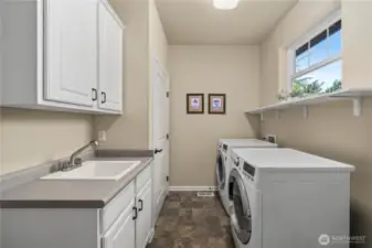 Laundry room includes ample storage and a convenient utility sink