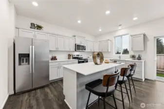 Large kitchen island with quartz counters and breakfast bar all standard. Actual home is under construction and colors, materials, and finishes may vary. See site agent for details.