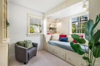 Main floor bedroom featuring a custom built-in bed and shelving, new carpet, and east and north facing windows.  Could be a well suited home office or guest suite.