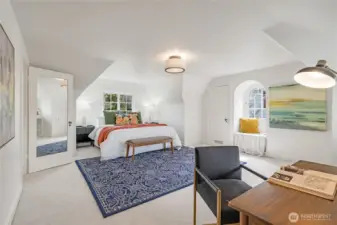 Huge upstairs primary suite with coved ceilings and windows, south and east facing light, pictured here with a king bed. Opens to an oversized walk-in closet with built-in desk, cabinets, and drawers.