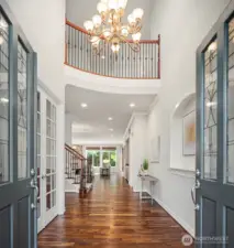 Soaring two-story ceilings, rich acacia hardwood floors, and an elegant chandelier create a grand yet welcoming entry foyer that immediately impresses. Flanking French doors with beautiful glass detailing add a touch of sophistication while flooding the space with natural light.