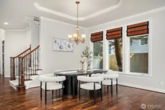 This elegant formal dining room impresses with its tray ceiling, refined chandelier, and rich acacia hardwood floors, offering a sophisticated setting for hosting dinner parties and special gatherings. The generous proportions and classic white millwork create a timeless backdrop that complements any décor style.