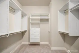 One of two generous walk-in closets in the primary suite, this beautifully appointed space features floor-to-ceiling custom shelving, hanging rods, and dedicated drawer space designed to accommodate an extensive wardrobe with ease. The bright, well-organized layout ensures that every inch of storage is maximized, adding a true luxury touch to this already exceptional primary retreat.