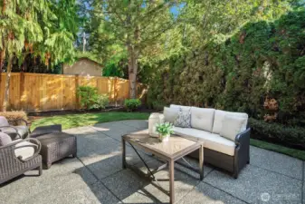 This inviting backyard patio offers a private and peaceful outdoor living space, beautifully framed by lush mature landscaping and tall privacy fencing that creates a true backyard sanctuary. The generous paver patio with comfortable seating provides the perfect setting for relaxed outdoor gatherings or quiet evenings enjoying the serene, park-like surroundings.