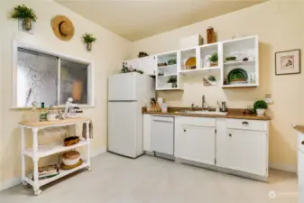 This adorable kitchen features easy-to-maintain luxury vinyl flooring, white millwork, and this charming pass-through window.