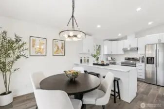 Open dining area seamlessly connected to the kitchen, showcasing modern finishes, stainless steel appliances, and a functional breakfast bar.
