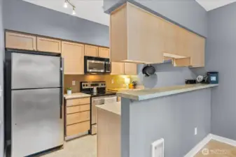 The functional kitchen offers ample cabinetry, stainless steel appliances, and a convenient breakfast bar.