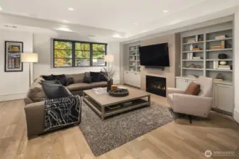 Custom built-in library/media cabinets flank the gas fireplace in the rec room.