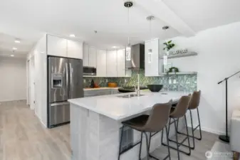 As you walk down the hallway you are greeted by the good sized and recently updated kitchen with a dedicated dining space (to the left of this photo), and open concept kitchen/dining/living room. To the left of the refrigerator and down the hallway are the two bedrooms, which would be on your left.