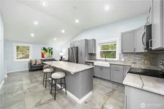 The kitchen offers a huge island with barstool seating, quartz countertops, and stainless steel appliances for a stylish setting any chef would love. An adjoining deck perfect for entertaining looks out over the front yard. A primary suite—one of two in this home—comes with it’s own bath and opens out to the deck. A